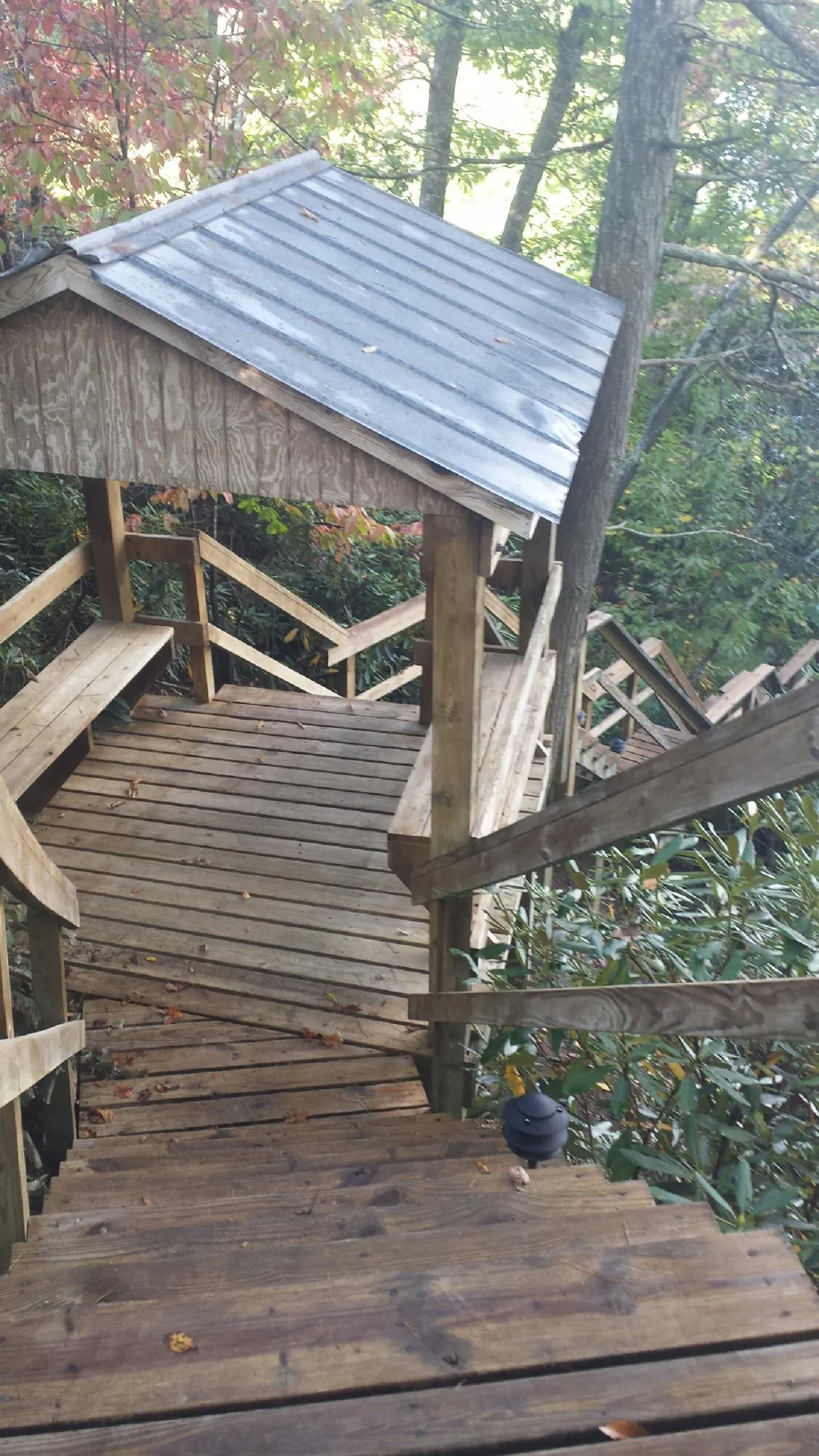 Metal roofed shelter over wooden steps on a wooded walkway — Skylight Repair & Installation work by our crew in Glenwood
